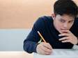 high school student holding a pencil leaning over a sat test 