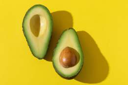 a halved avocado on a yellow background