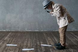 little boy with a magnifying glass looking at footprints